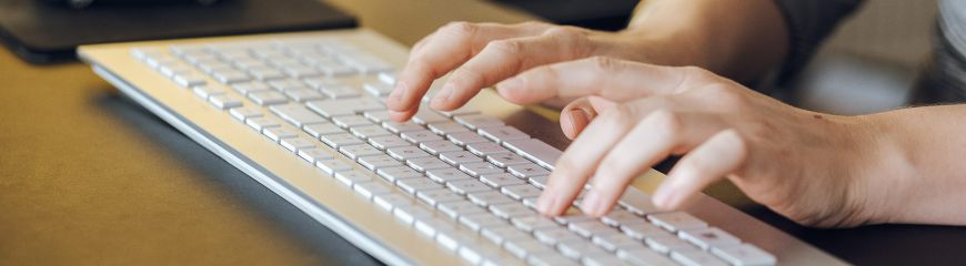 Hände die auf eine Tastatur tippen