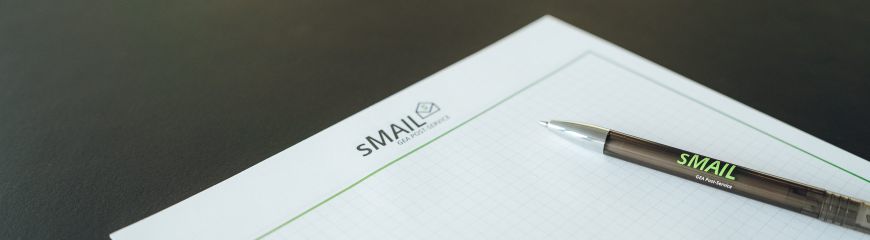 Ein Block (mit dem sMAIL Logo) und eine Kugelschreiber liegen auf einem Tisch