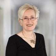 Eine Frau mit einer kurz Haar Frisur und einem schwarzen dünnen Pullover