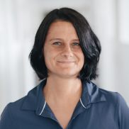 Eine Frau mit etwas kürzeren Haaren die ein dunkelbaues Polo Tschirt an hat