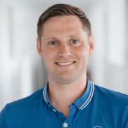 EIn Mann mit einer kurz Haarfrisur und einem blauen Polo Tshirt